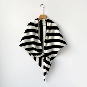Close-up of black and white striped wool blend knit shawl on wooden hanger with a stylish knot