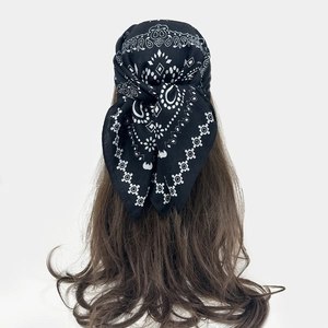 Detail of a black paisley bandana tied as a hair accessory on long brown hair