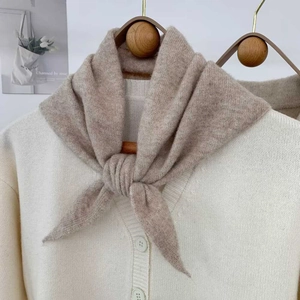 Texture détaillée du tricot de l'écharpe triangle avoine sur un cintre en bois