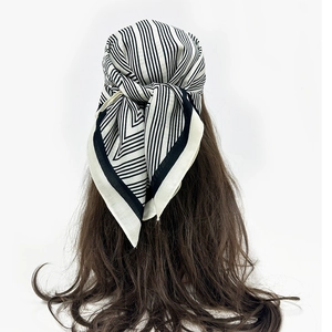 Detail view of black and white striped silk scarf tied as a hair accessory for women