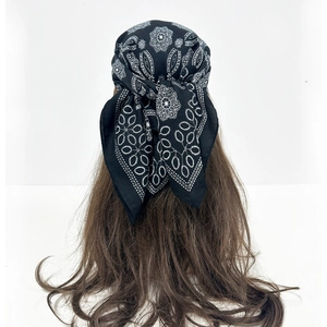 Detail of black paisley headscarf with white mandala patterns tied on a mannequin