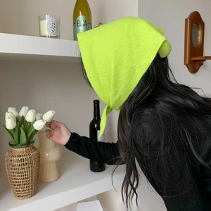 Détail d'un foulard triangle en tricot vert fluo porté en bandeau chaud
