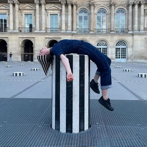 Photo artistique d'une femme en combinaison denim bleu foncé sur colonne rayée