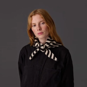 Vue détaillée d'un châle en maille rayée noué sur une veste noire pour femmes