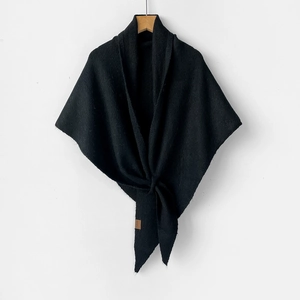 Close-up of black knitted wool shawl featuring a knotted front and textured stitch detail