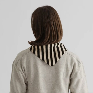 Gros plan sur le châle en tricot rayé noir et blanc porté sur un sweat-shirt gris clair