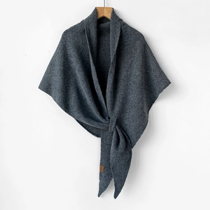 Detail of dark grey wool knit shawl with coarse texture and leather brand label