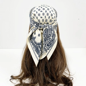 Detail of paisley print cotton square scarf in cream and navy blue worn as a headpiece