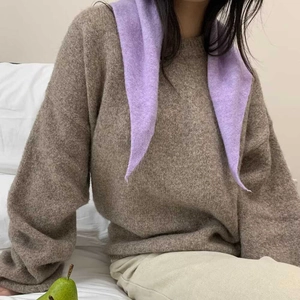 Détail d'une écharpe en tricot lavande avec un pull marron surdimensionné moelleux