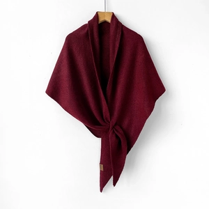 Detailed texture of burgundy wool blend knit shawl with elegant brown leather logo tag