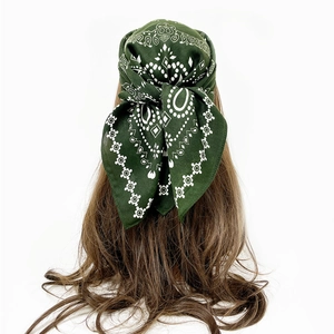 Detail of dark green paisley cotton headscarf tied on a model with white geometric patterns