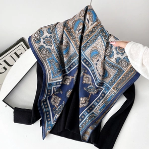 Detail of navy silk scarf with paisley patterns worn over a black sweater
