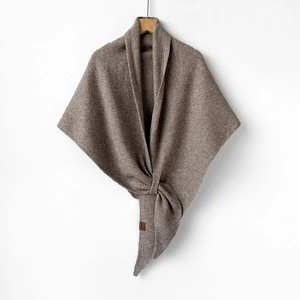 Close-up of the premium wool knit texture and brand label on a brown scarf shawl