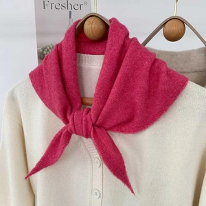 Détail d'une écharpe triangle en tricot rose rouge nouée en nœud sur un cardigan