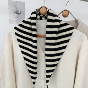 Détail d'un cardigan en laine blanc cassé avec boutons mats et châle en tricot rayé