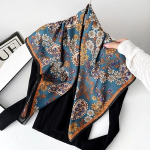 Detailed view of floral paisley pattern on silk square scarf with contrast border