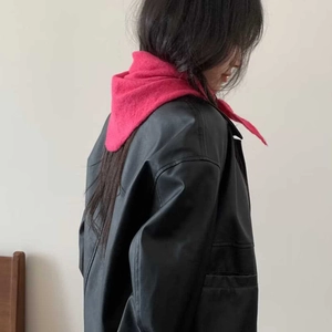 Gros plan sur la texture d'une écharpe triangle en maille rose vif avec veste en cuir