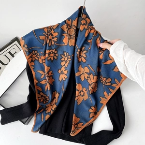 Detail of elegant navy and orange floral silk scarf draped over a black sweater