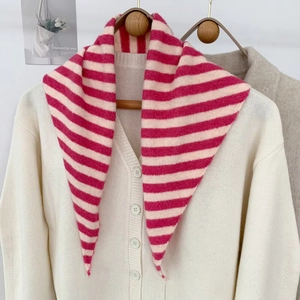 Détail de l'écharpe triangle tricotée à rayures rose et beige sur cardigan blanc