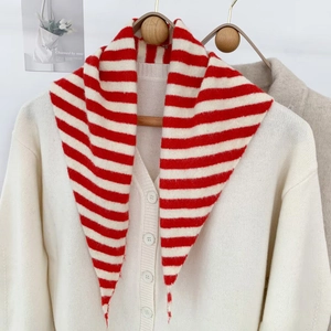 Détail de l'écharpe triangulaire en tricot rayé rouge et blanc sur un cardigan blanc