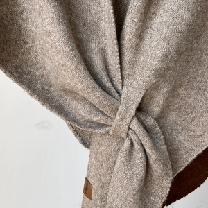 Heather tan knitted wool blend shawl featuring a knot design and brown leather label detail