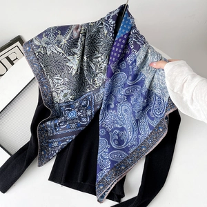 Detail of silk-feel scarf featuring navy blue paisley patterns on a black sweater