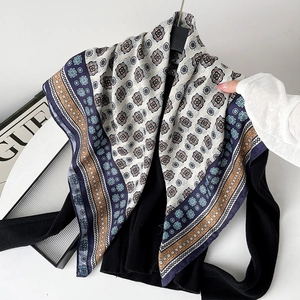 Detail of herringbone silk scarf with blue floral patterns on a black sweater