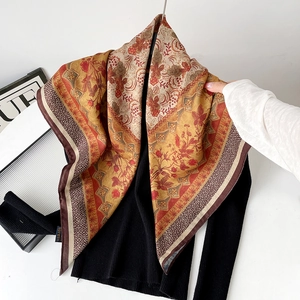 Detail of bohemian floral pattern silk scarf on black sweater with warm orange tones