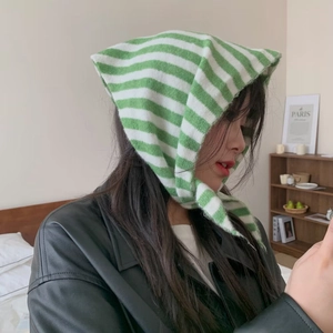 Détail d'une capuche tricotée à rayures vertes et blanches avec liens sur veste en cuir