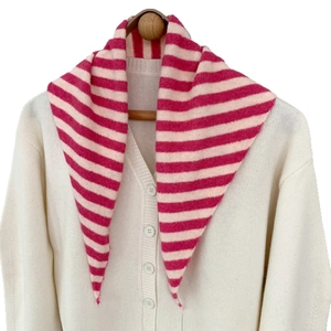 Détail d'une écharpe en maille rayée rose drapée sur un cardigan en laine beige