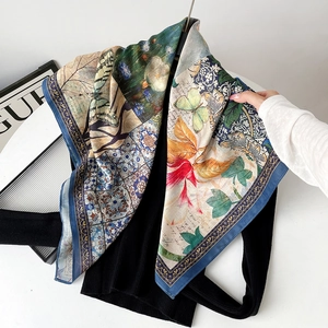 Detailed close-up of patterned silk scarf featuring floral and butterfly art designs