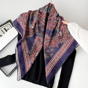 Detail of silk square scarf with purple paisley pattern styled on a black sweater