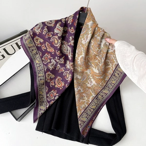 Detail view of purple paisley silk scarf draped over black knitwear with elegant texture