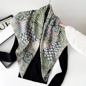 Detailed macro view of bohemian paisley silk scarf texture on a black knit top