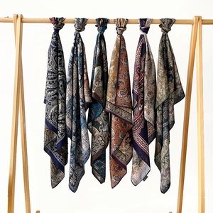 Silk square scarves with paisley and floral patterns displayed on a wooden rack