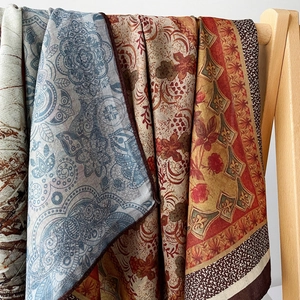 Silky herringbone scarf with paisley and floral patterns displayed on a wooden hanger