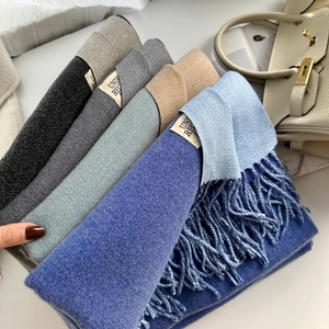Détail d'écharpes multicolores en cachemire avec franges et étiquettes tissées sous lumière