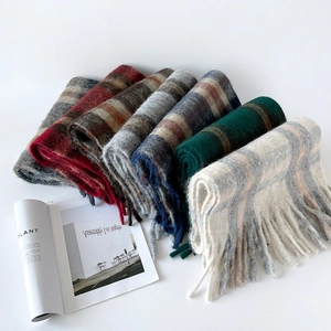 Close-up of thick wool scarves with classic plaid patterns and decorative fringe edges
