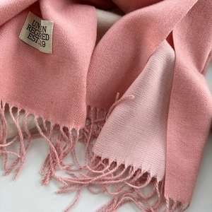 Gros plan du châle en cachemire rose avec bordures à franges et étiquette tissée
