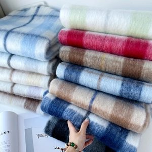 Detail of soft mohair plaid scarves in various colors stacked on white background