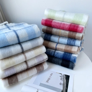 Detailed view of stacked colorful plaid mohair scarves with soft brushed wool textures