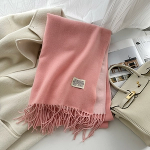 Détail d'une écharpe rose en cachemire avec étiquette de marque et bords à franges fins