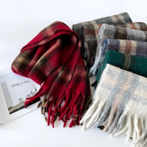 Close-up of assorted thick plaid wool scarves with long tassels and soft textures