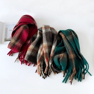 Detail of thick plaid scarves with tassels in burgundy, caramel grey and forest green