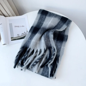 Detailed view of grey checkered mohair scarf with soft fringe on a clean white table