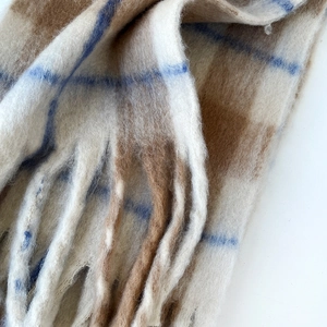Close-up of thick checkered mohair winter scarf with cream and brown plaid fiber texture