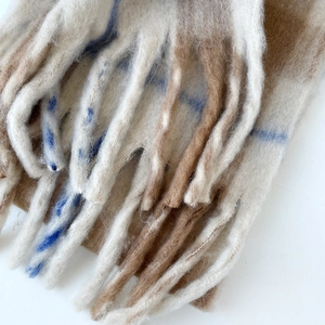 Macro shot of plaid mohair scarf texture with thick tassels and cream brown check pattern