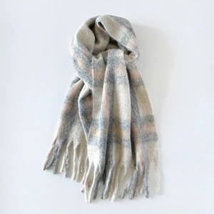 Close-up of soft brushed texture and fringed edges on a plaid wool scarf for women