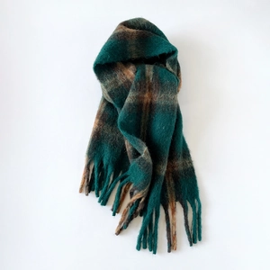 Close-up detail of mohair plaid scarf showing dark green texture and tassel fringe