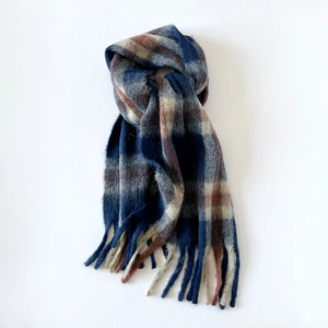 Detailed view of thick checkered scarf featuring navy and beige patterns with fringe edges